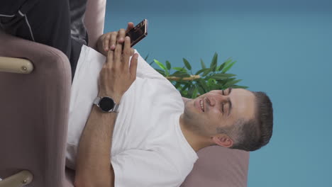 Vertical-video-of-Man-smiling-at-phone-message.